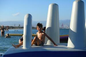 Caucasian boy of nine year old having fun at the inflatable beach aqua slide photo