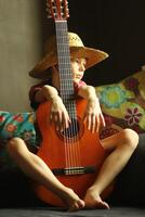 Portrait of a caucasian boy wearing a straw hat and playing the guitar photo