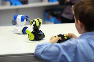 Boy playing battle fighting robots with remote control. Robotics, STEM photo