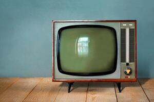 Vintage TV set on wooden table against old blue wall background photo
