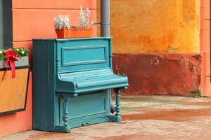 Vintage weathered aquamarine piano outdoor in the street downtown photo