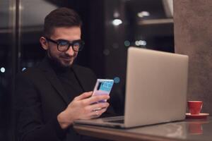 Young man using a smartphone at his office during the night. photo