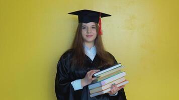 caucasiano menina aluna detém muitos livros enquanto ficando dentro frente do Câmera com graduando diploma dentro dela mãos. mestre do teologia video