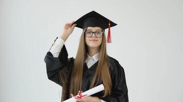 een jong Kaukasisch vrouw Bij de Universiteit Bij de meester mantel met een hand- versieringen haar diploma, en met de andere hand- versieringen de rand van de kapel en wonderen Bij de camera. meester van brieven video