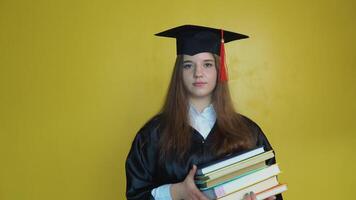 Caucasian young girl student holds many books while staying in front of camera on yellow background video