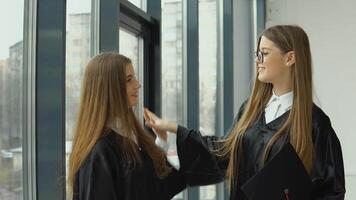 Two young happy graduates communicate happily by the window video