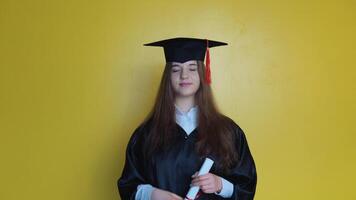 caucasiano menina aluna mostra dedo acima enquanto ficando dentro frente do Câmera com graduando diploma dentro dela mãos video