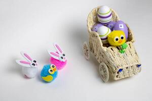 Lilac Easter eggs and small toys bunnies birds in a toy wicker car. The concept of Easter photo