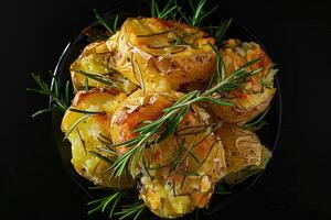 AI generated Crushed, smashed potatoes baked with rosemary and thyme. Black background. Top view. photo