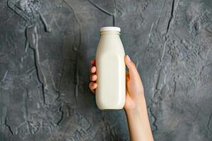 AI generated Hand holding bottle of milk on gray background. With space for add text. photo