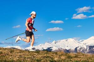 Sporty man practices nordic walking in the hills photo