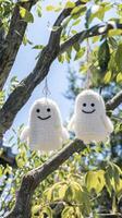 AI generated Two cute white smiling ghost dolls cotton hanging on a tree, green leaves background. photo