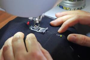 concepto de costura. manos femeninas trabajando en una máquina de coser moderna con algunas telas y textiles foto