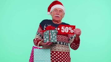 Elderly man in Christmas sweater showing gift box and 50 Percent discount inscriptions banner text video