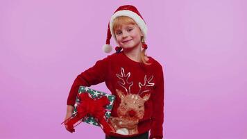 Cheerful girl in Santa sweater presenting two Christmas gift boxes stretches out her hands to camera video