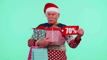 Mature man in Christmas sweater showing gift box and 70 Percent discount inscriptions banner text video