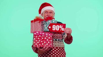 Senior man in Christmas sweater showing gift box and 90 Percent discount inscriptions banner text video