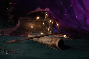 A magic wand carved from wood lies on a scroll with spells on a velvet green cloth among magical paraphernalia on a shining background with lights. Wizard's Things Close-Up photo