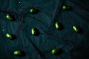 Shiny green eggs scattered on the folds of fabric photo