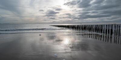 panorama ver norte mar costa, melancólico puesta de sol detrás lluvia nubes foto