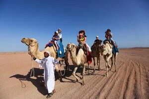 Sharm El Sheikh, Egypt - March 18, 2020 Tourists riding camels in the Egypt desert. photo