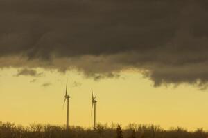 two windmills with dark rainclouds and yellow color photo