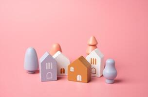 Cute town made of figures on a pink background. Wooden figurines toys. Buy a house. Good housing. Mortgage. Pastel pink colors. photo