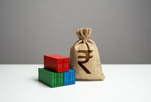 Stack of shipping containers and indian rupee money bag. GDP and production. Import or export. Tariffs and tax collections. Production of containers. Trade, economics and transport industry. photo