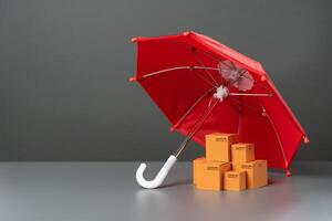 Boxes with goods under a red umbrella. Cargo and parcel insurance. Warranty obligations. Logistics security. Protection of national producer market. Imposing protective duties on foreign competitors. photo