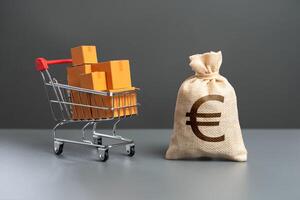 Shopping cart with boxes of goods and euro money bag. Purchasing power of buyers. Trade and retail. Taxes and income. Consumer prices. Import of products. photo