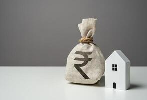 House and indian rupee money bag. Investments in the purchase of real estate. Repair and service. Make a deal. Insurance. House price, property valuation. photo