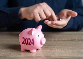 cerdito banco y 2024. ahorro planes para el año adelante. ahorros y inversiones. colección de donaciones banco depósito. aumento fondos para tu sueño. reducir costos salvar para Jubilación. acumulando dinero. foto