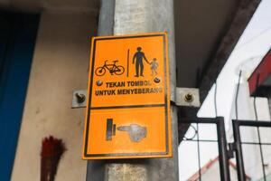 a sign with text press a button if pedestrians want to cross. surabaya, indonesia - 6 maret 2024 photo
