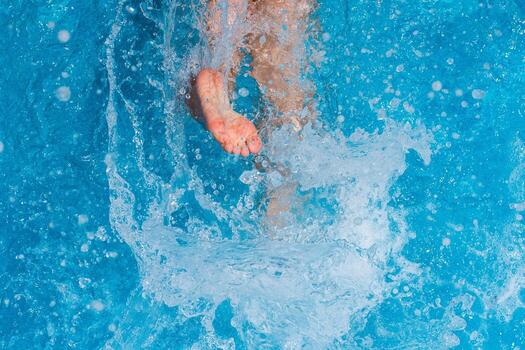Child splashing in the cool water of a pool in summer photo