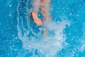 niño salpicaduras en el frio agua de un piscina en verano foto