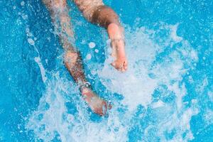 niño salpicaduras en el frio agua de un piscina en verano foto