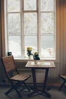 Empty table and antique wooden chairs near a window photo