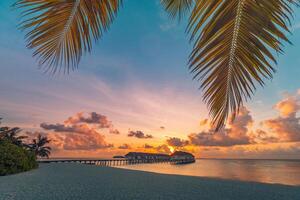 Amazing beach landscape. Beautiful Maldives sunset seascape view. Horizon colorful sea sky clouds, over water villa pier pathway. Tranquil island lagoon, tourism travel reflection. Exotic vacation photo