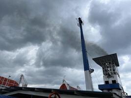 Black smoke causes air pollution coming from the exhaust pipes of ships in the port photo