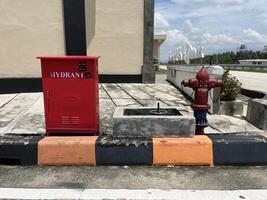 A red hydrant for storing water during a fire incident is installed on the side of the road photo