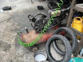 Car repair shop, air pump machine compressor, pile of used oil bottles and used tires photo