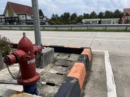 A red hydrant for storing water during a fire incident is installed on the side of the road photo