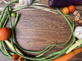 Vegetables tomatoes carrots and other on wooden table close up photographed from above photo