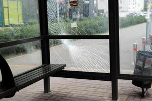 Broken glass at the bus stop. Public transport station vandalised by the glass windows. cracks of tempered glass photo