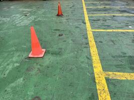 Road symbol cone in rest area parking lot and ship with yellow guide lines for cars photo