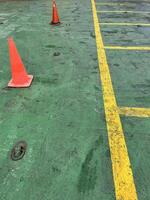 Road symbol cone in rest area parking lot and ship with yellow guide lines for cars photo