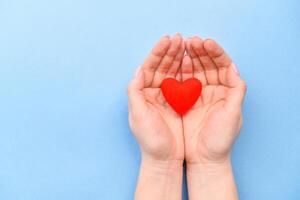 Red symbol heart in hands on a blue background. The concept of Valentine's Day and Women's Day. Top view, place for text. a life. photo