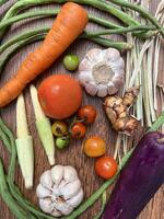 Vegetables tomatoes carrots and other on wooden table close up photographed from above photo