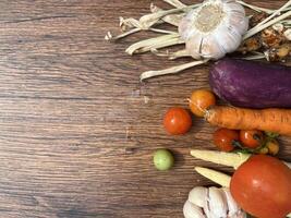 Vegetables tomatoes carrots and other on wooden table close up photographed from above photo