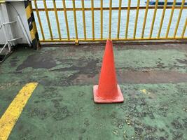 Road symbol cone in rest area parking lot and ship with yellow guide lines for cars photo